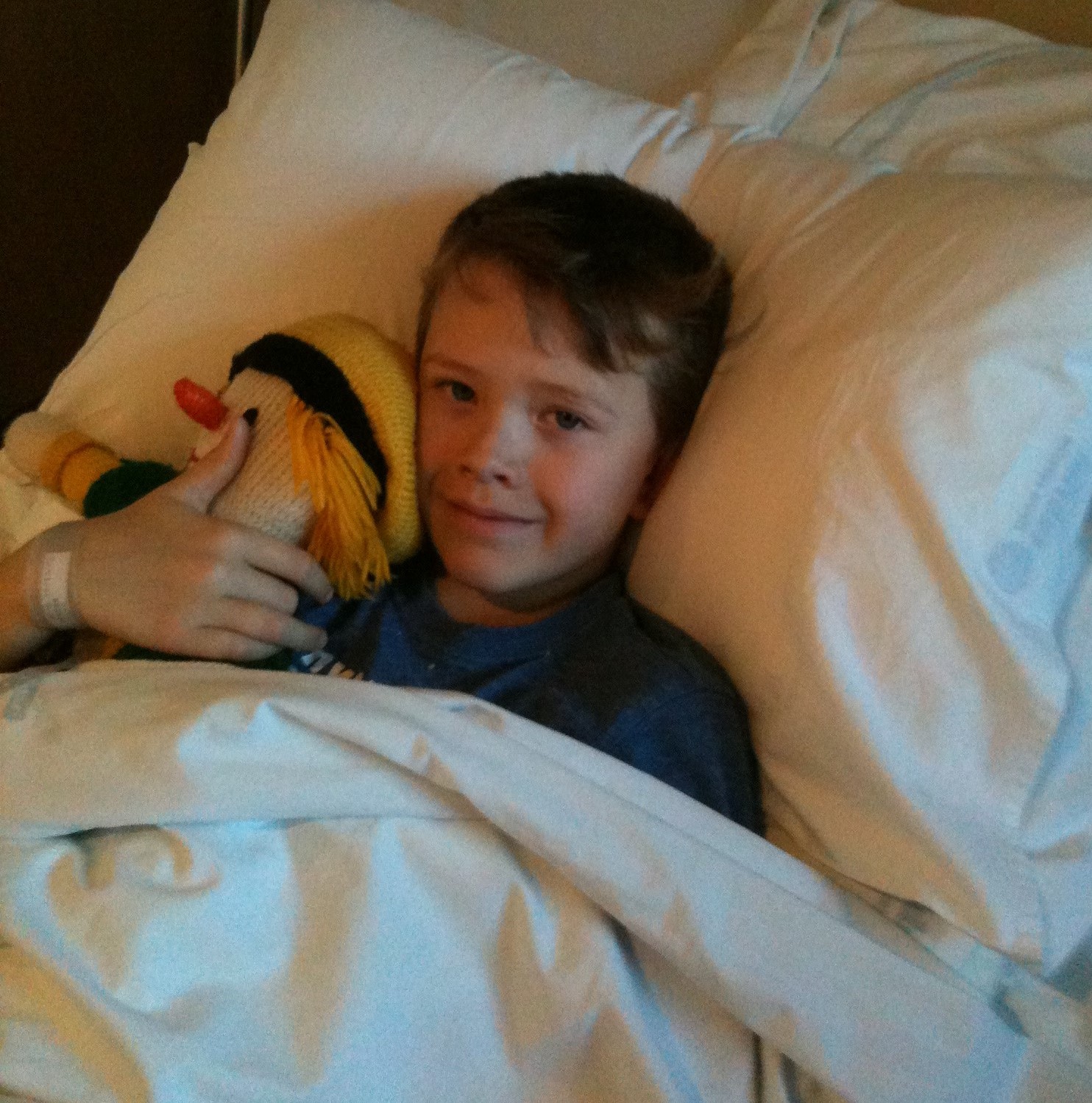 Nate in hospital bed cuddling a teddy