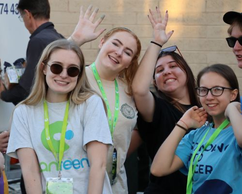 A group of young people impacted by cancer smiling at the camera, wearing Canteen shirts